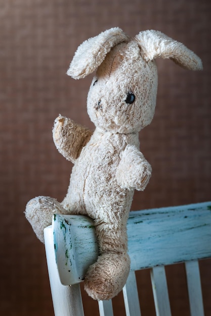 Vintage toy rabbit Old vintage soft toy hare sits in old white chair