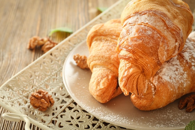 Vintage tray with tasty croissants on wooden table closeup