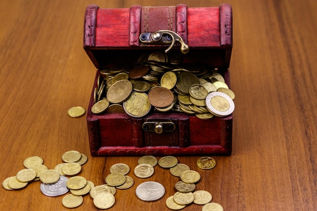 Vintage treasure chest full of golden coins on wooden background