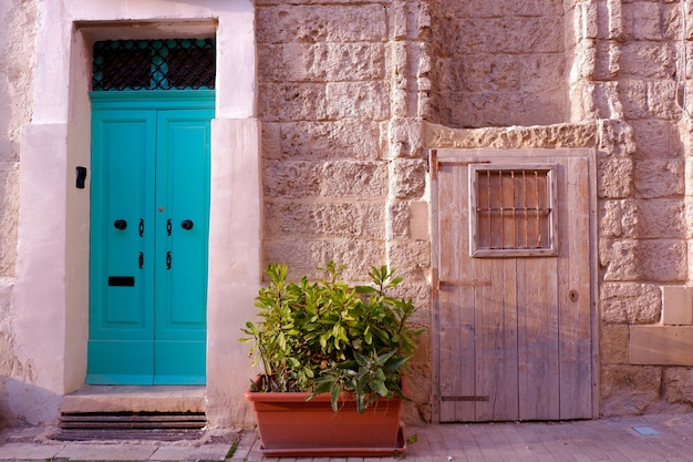 Vintage turquoise deur een potplant en een kleine bruine armoedige kelder houten deur straat Malta