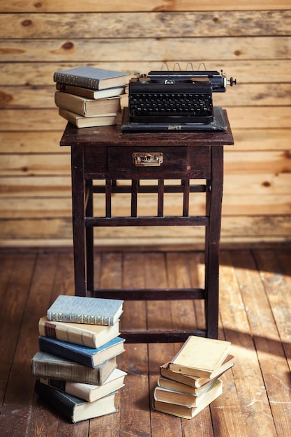 Vintage typemachine en boeken op tafel met blanco papier op houten bureau