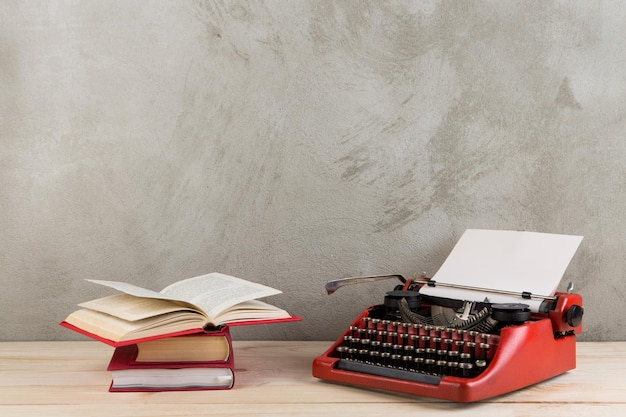 Vintage typewriter and books on the table with blank paper on wooden desk