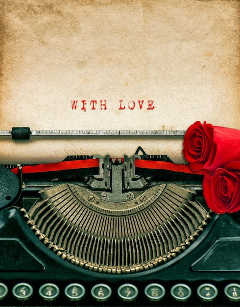 vintage typewriter and red rose flowers. aged textured grungy paper. sample text with love. valentines day concept