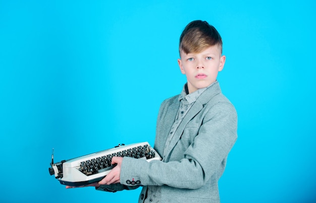 Vintage typografie Leuke jongen met een schrijfmachine Klein kind met een vintage schrijfmachine Slim kind met een mechanische vintage machine Klein jongen met een vintage schrijfmachine op blauwe achtergrond