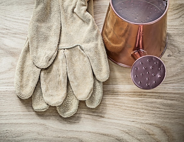 Vintage watering can protective gloves on wooden board agriculture concept