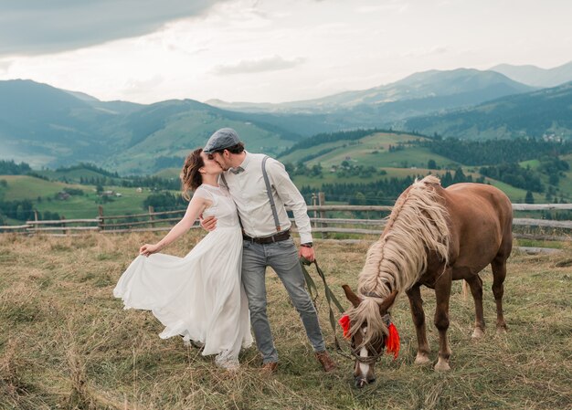 ピークの丘の上の馬と牧場で新郎新婦のビンテージのウェディング