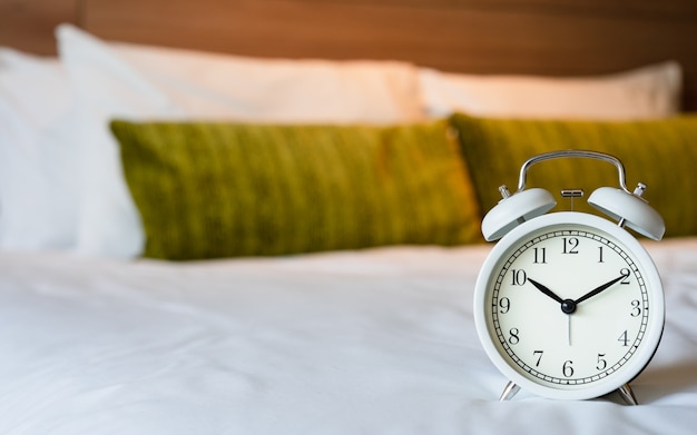 Vintage white alarm clock on bedroom. 