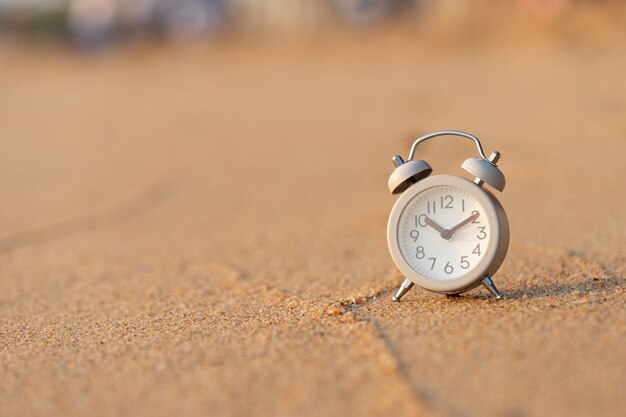 Vintage White Alarm Clock on the sand