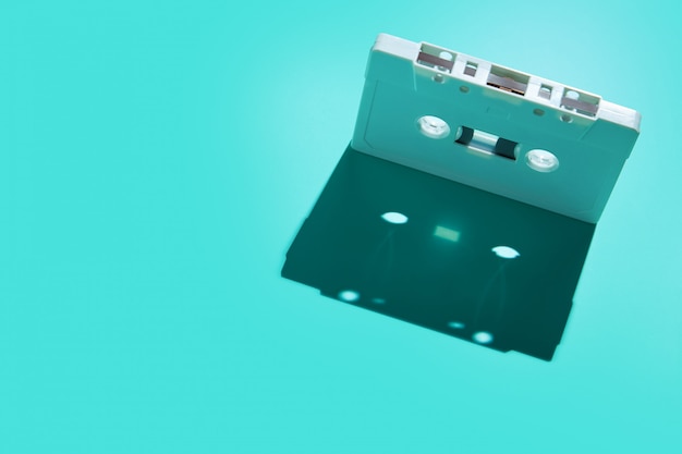 Vintage white audio cassette tap with shadow on colored background