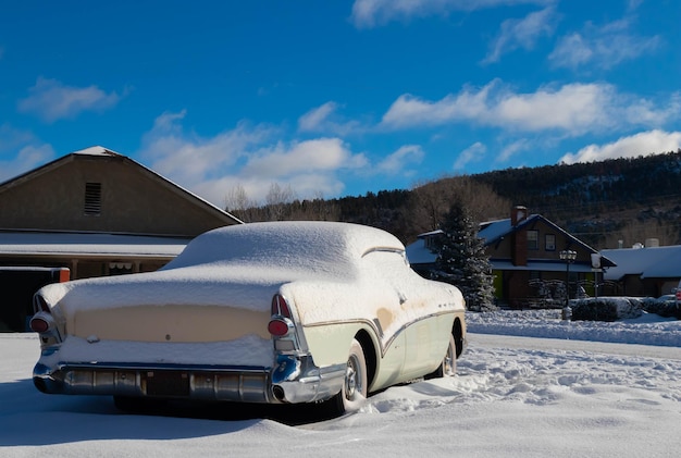 Vintage witte auto bedekt met sneeuw achtergelaten in een klein dorpje