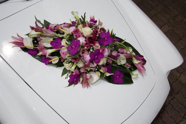 Vintage witte trouwauto versierd met paarse bloemen