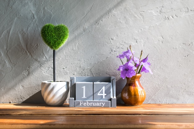 Vintage wood calendar for February 14 with green heart on wood table love and valentine's day concept background, backdrop.