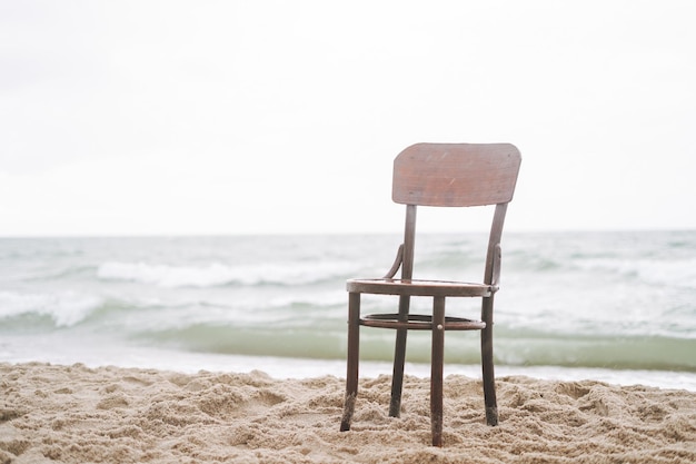 사진 폭풍에 바다 의 모래 위에 있는 빈티지 목조 의자