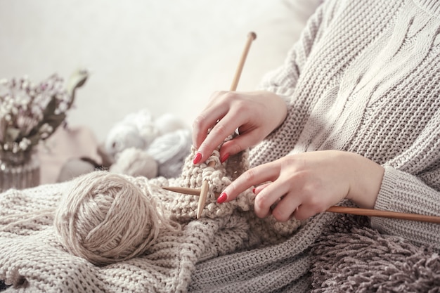 Vintage wooden knitting needles and yarn in woman's hands