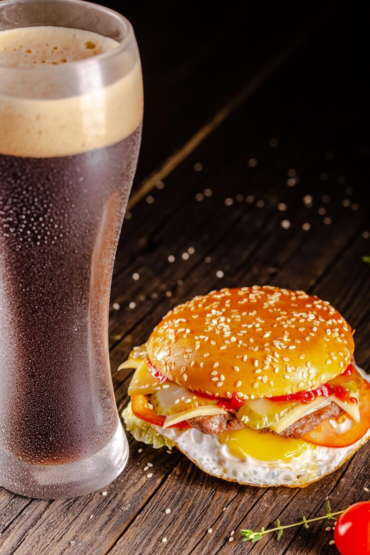 Photo vintage wooden table, on a cutting board, juicy burger white bread, cheese, meat sliced pork, beer i