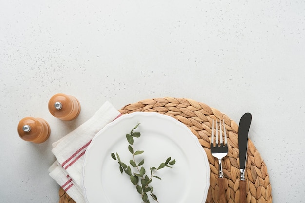 Vintage zero waste silverware Rustic vintage set of white plate wooden spoon and fork on napkin for dishes from water hyacinth on light gray concrete background Empty dishes Top view Mock up