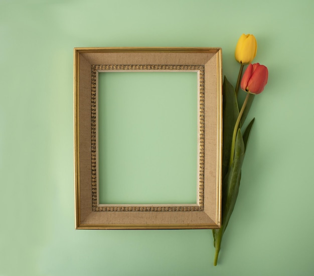 Фото vintageretro и элегантная золотая рамка с красными и желтыми тюльпанами минимальная концепция пространства для копирования на бледно-зеленом фоне