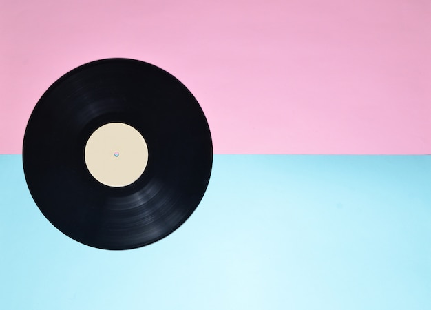 Vinyl plate on a blue pink pastel background. A trend of minimalism. Retro media from the 70s. Audio technology. Top view. Copy space.