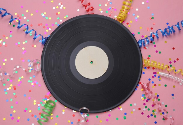 Vinylplaat en gekleurde streamer met confetti op een roze achtergrond muziekdag