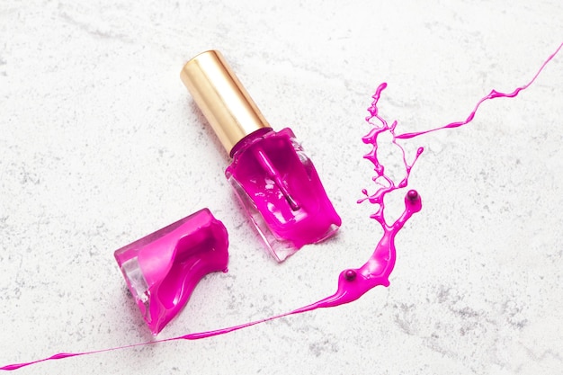 Violet broken nail polish bottle on marble purple dye color splash and suffusion