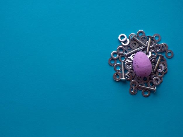 Violet Easter egg on blue background with metal screws