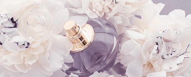 Photo violet fragrance bottle as luxury perfume product on background of peony flowers parfum ad and beauty branding