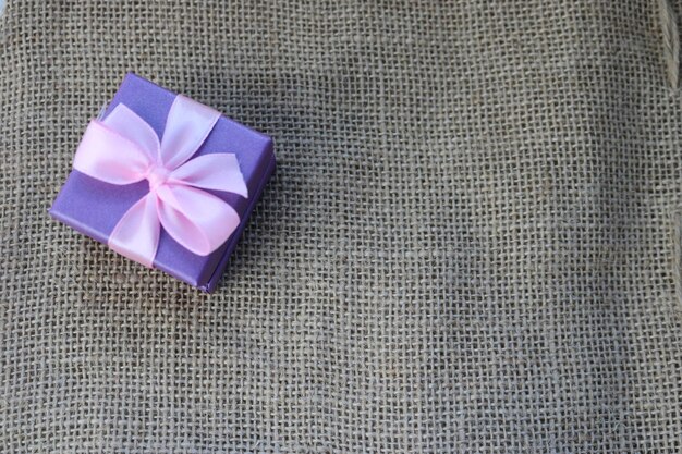 Violet gift beautiful festive cardboard small gift box with a pink bow on a background of brown