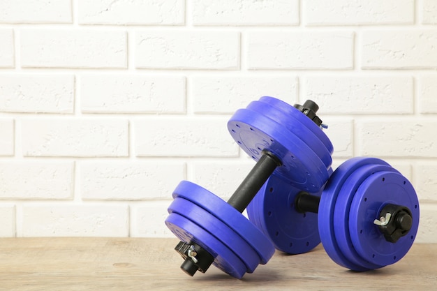 Violet gym dumbbells on white brick wall