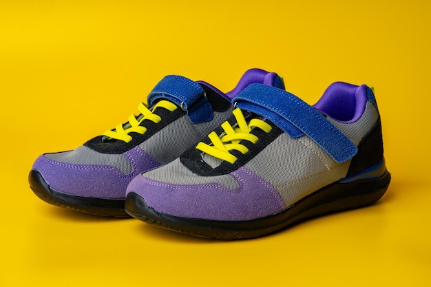 Violetblue female sneakers on yellow studio background