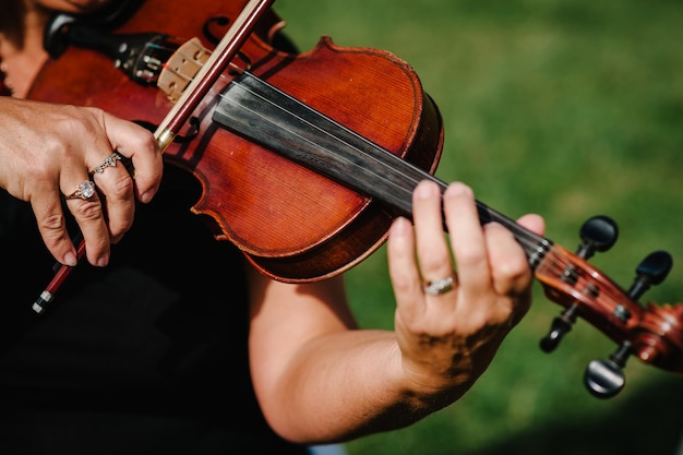 Violin player hands Violinist playing violin on background of field Performance on nature Close up of musical instruments Classical music professional cello player solo Unrecognizable person