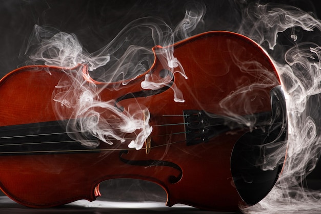 Photo violin and smoke wonderful details of a beautiful violin with smoke in the environment dark background selective focus