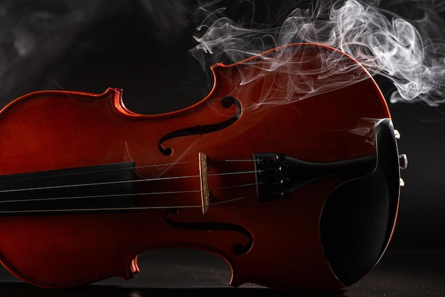 Photo violin and smoke wonderful details of a beautiful violin with smoke in the environment dark background selective focus