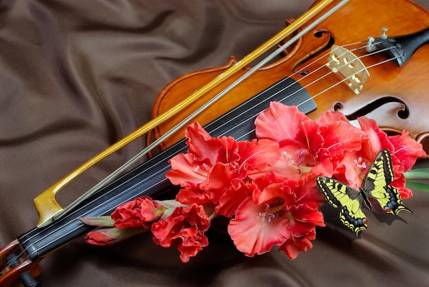 A violin with a flower on it sits on a brown cloth.