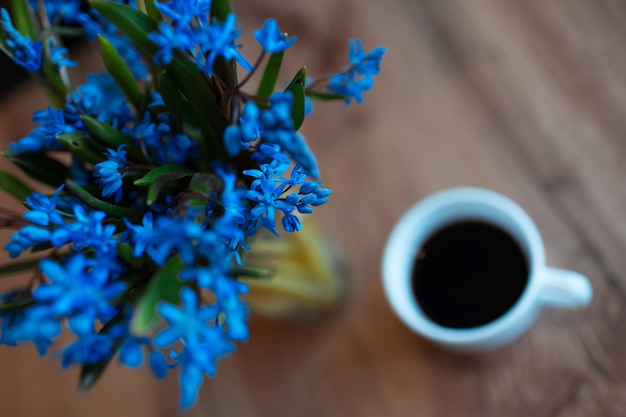 Viooltjes bloemen op achtergrond van houten tafel en kopje koffie.