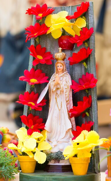 Premium Photo | Virgin mary statue figure with red flowers and ...