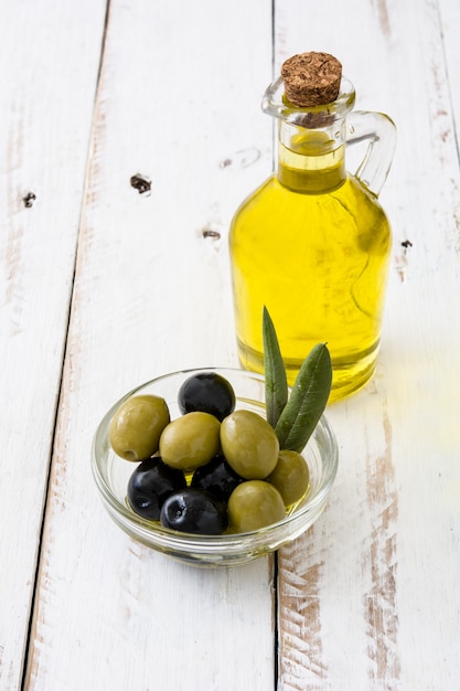 Photo virgin olive oil in a crystal bottle on white wooden table