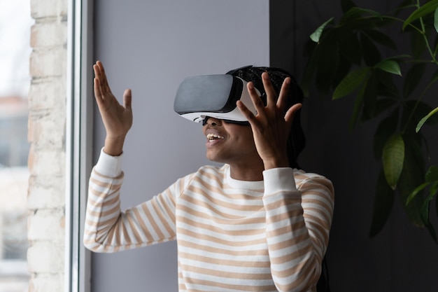 Intrattenimento virtuale a casa donna africana felicissima in cuffia vr che gioca a un videogioco interattivo