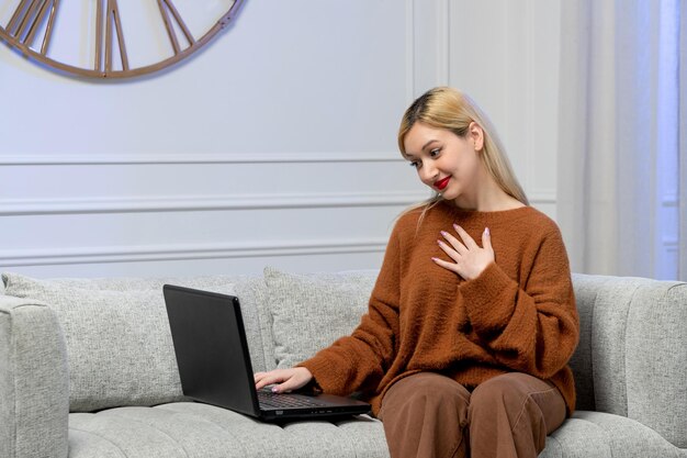 Virtual love cute young blonde girl in cozy sweater on distance computer date holding chest