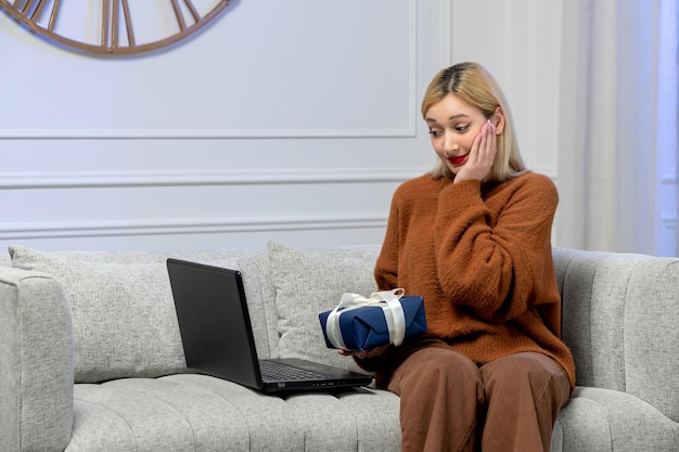 Virtual love cute young blonde girl in cozy sweater on distance computer date holding present