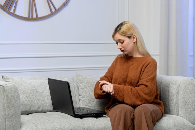 Virtual love cute young blonde girl in cozy sweater on distance computer date looking at clocks