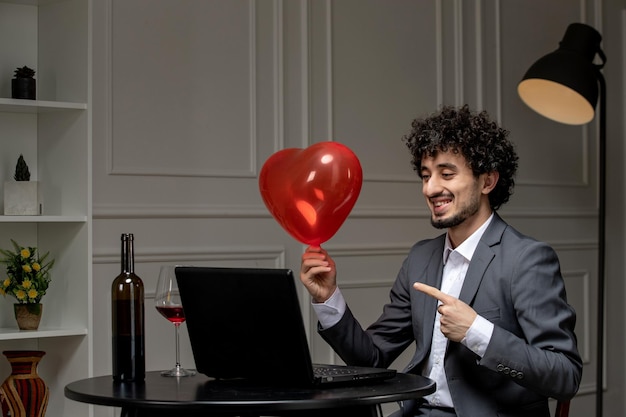 Virtual love handsome cute guy in suit with wine on a distance computer date holding red balloon