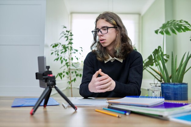 Virtual online lesson teenager guy learns remotely using a smartphone