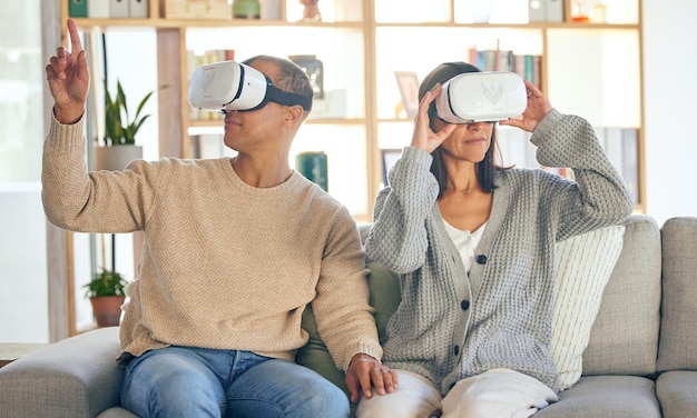 Virtual reality 3D en een stel in de interactieve metaverse terwijl ze samen op een bank in de woonkamer van een huis VR-bril spelen en gamen met een man en een vrouw in hun huis om te ontspannen of videogames te spelen