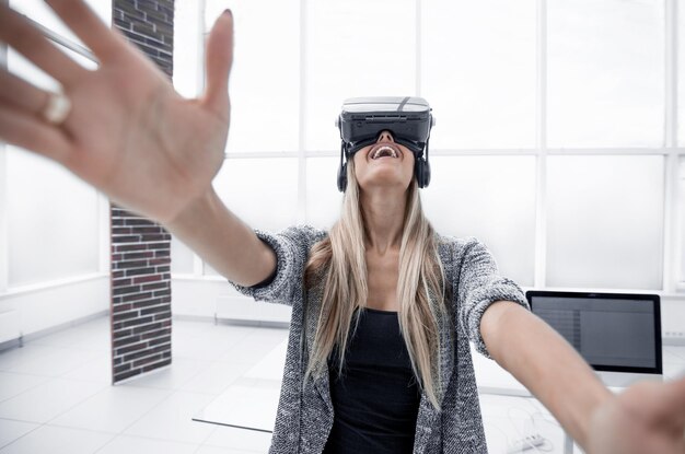 Virtual reality-bril Zelfverzekerd lachend meisje dat zich gelukkig voelt terwijl ze een virtual reality-apparaat draagt en naar de pictogrammen op het transparante scherm wijst