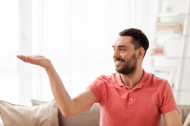 virtual reality, entertainment and people concept - happy man holding something imaginary on palm at home