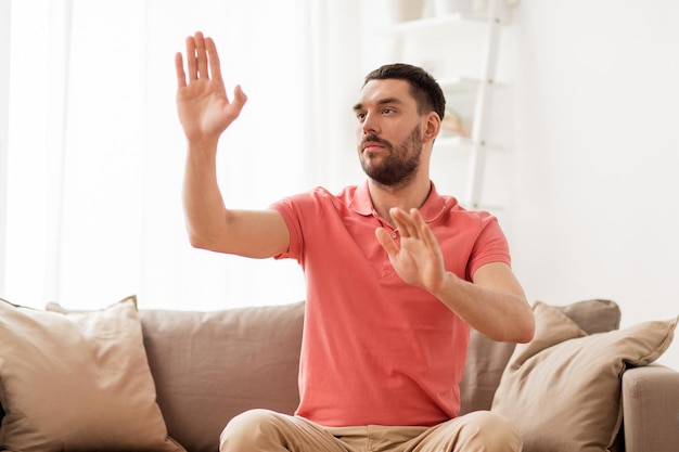 virtual reality, entertainment and people concept - man touching something imaginary at home