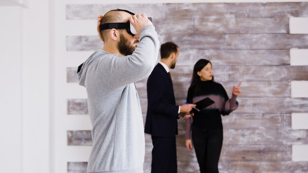 Virtual reality ervaren met headset in nieuw appartement en vrouw in gesprek met makelaar op de achtergrond.