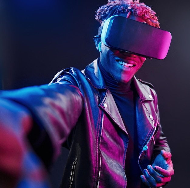 Virtual reality experience Futuristic neon lighting Young african american man in the studio