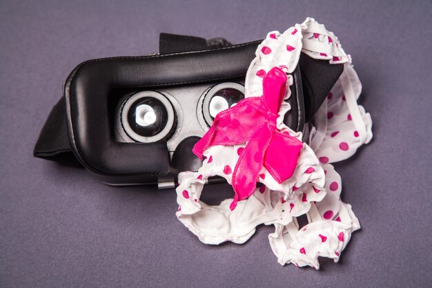 Photo virtual reality glasses for mobile devices with dotted pink white lingerie with bow on top, vr technology used for porn vr video in adult entertainment.