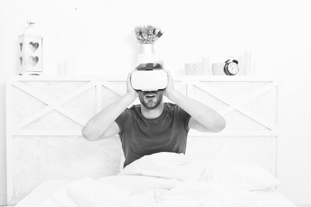 Virtual reality is echt hier Blanke man met virtual reality-headset in slaapkamer Knappe man met virtual reality-apparaat in bed De volgende generatie virtual reality